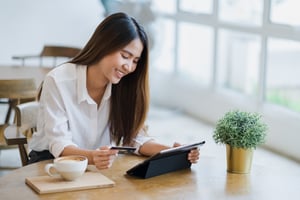 Young woman makes purchases on tablet at coffee shop